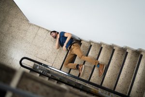 A man lying on the floor with injuries sustained from falling down the stairs.