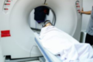 An out-of-focus image of a person entering a CAT scan machine.