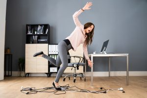 A woman in an office tripping over some loose wires.