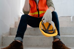 A construction industry worker sitting on a set of stairs after a building site accident