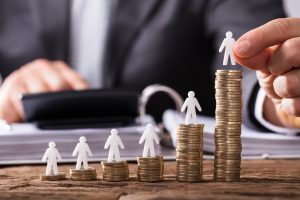 Piles of coins representing loss of earnings compensation with paper figures standing on top