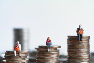 Three piles of coins representing personal injury compensation with small figurines sitting on top