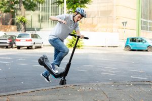 An e scooter rider crashing into a curb in a car park