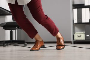 A person in red pants trips over a wire on the floor.