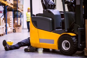 A person laying on the ground having been involved in a lift truck accident