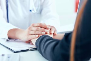 A healthcare provider holds a patient's hand after medical negligence.