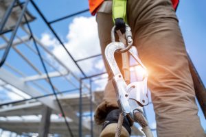 A construction worker has a harness attached as he begins to work at height.