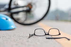 A bicycle, helmet and glasses lay in the road.