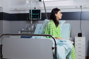 Woman, injured person with endometriosis diagnosis sat on bed.
